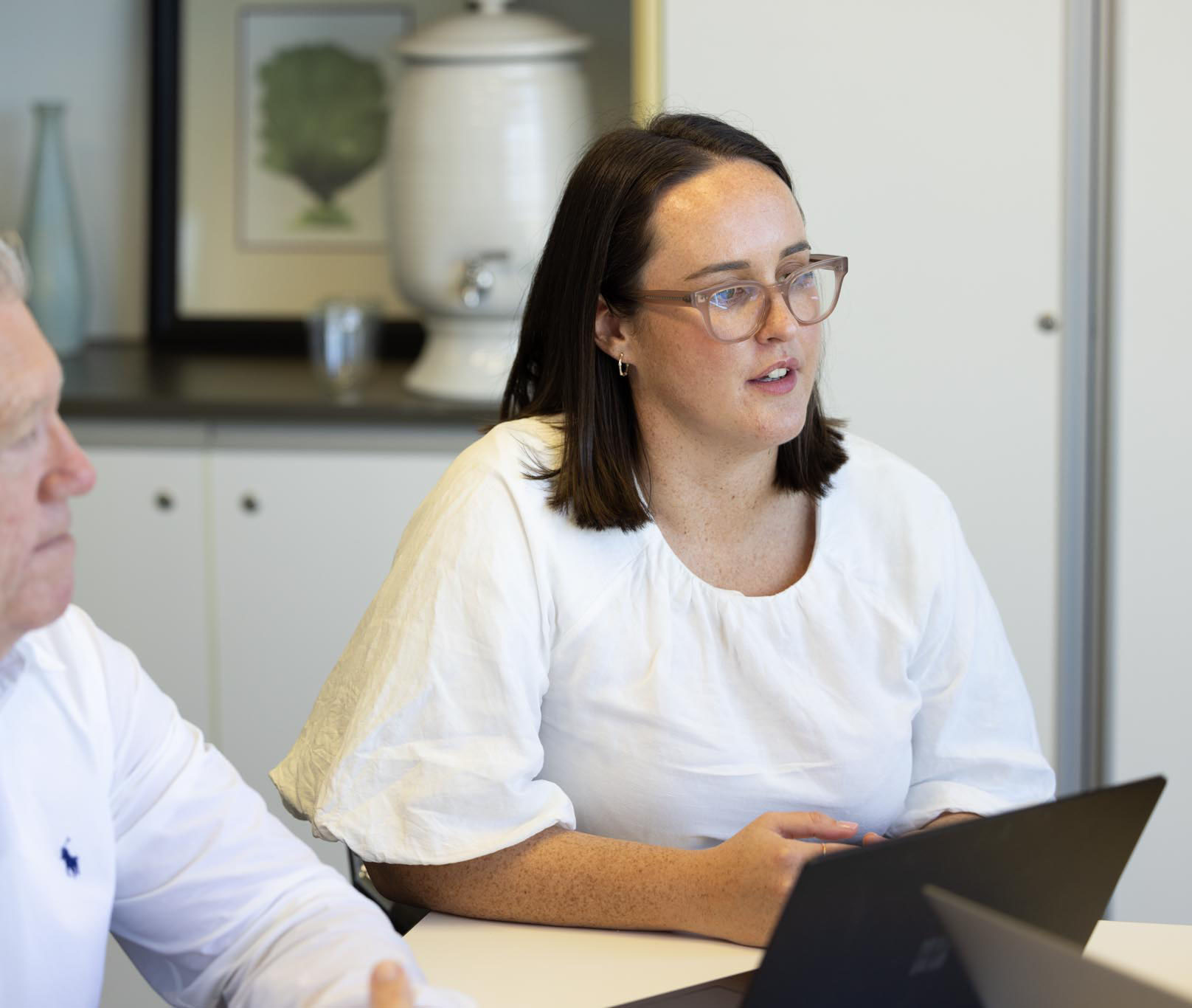 2 office ladies seated at a desk looking at a laptop